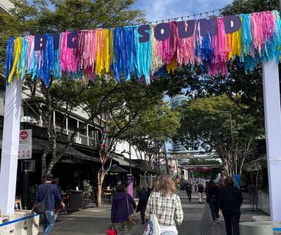 People walking into Fortitude Valley Mall, below a BIGSOUND Banner with streamers and rainbow colours