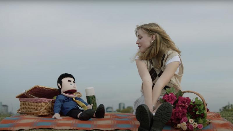 Kat Edwards looking at a puppet whilst sitting on a picnic blanket